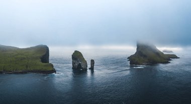 Faroe Adaları, Drangarnir uçurumu ve Tindholmur adalarının insansız hava aracı görüntüsü. Yazın yoğun bulutlar sırasında Atlantik Okyanusu 'nun koyu mavi suları ve yemyeşil sularıyla çekildi. Faroe Adaları, Danimarka
