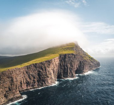 Faroe Adaları Traelanipa. Kölelerin kaya uçurumu okyanusun üzerinde Sorvagsvatn Gölü 'nün yanında yükseliyor. Faroe Adaları 'ndaki vajina adasında bulutlar ve mavi gökyüzü..