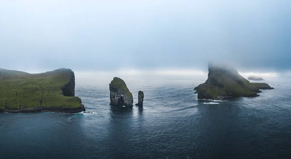フェロー諸島Drangarnir崖とTindholmur島の空中ドローンビュー。大西洋の濃い青色の水と緑豊かな緑と夏の激しい雲の間に撮影。デンマークのフェロー諸島 — ストック写真