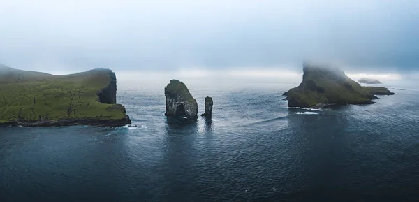 페로 제도 Aerial drone view of Drangarnir fruts and Tindholmur Islands. 여름에는 강렬 한 구름 속에서 북극해의 짙은 푸른 물 과 무성 한 녹색 의물에 잠겼다. 덴마크의 파로 제도 — 스톡 사진