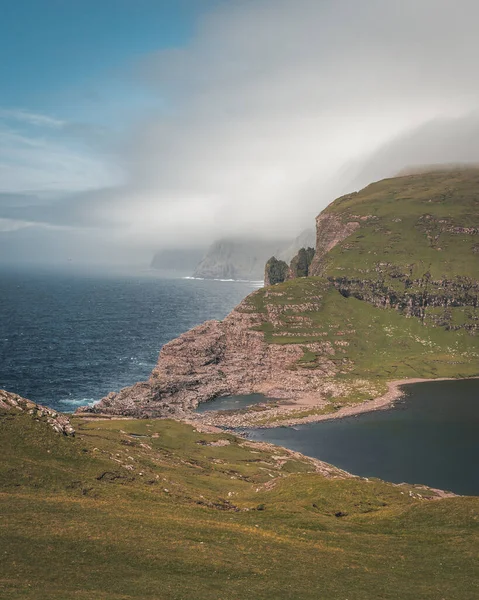 Faerské ostrovy Traelanipa, skalní útes otroků, se zvedá nad oceánem u jezera Sorvagsvatn. Mraky a modrá obloha během suommeru na ostrovním vagaru na Faerských ostrovech. — Stock fotografie