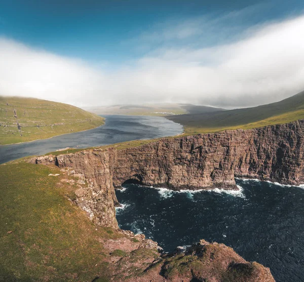 Faerské ostrovy Traelanipa, skalní útes otroků, se zvedá nad oceánem u jezera Sorvagsvatn. Mraky a modrá obloha během suommeru na ostrovním vagaru na Faerských ostrovech. — Stock fotografie