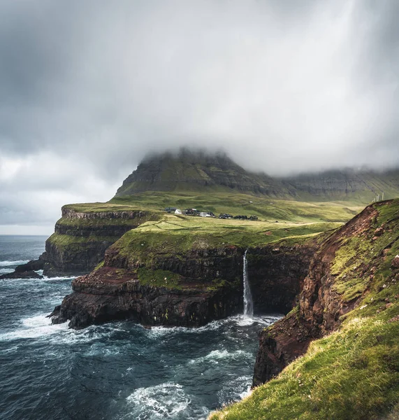 ガサドゥール村とMulafossurの象徴的な滝、 Vagar 、 Faroe諸島、デンマーク。北大西洋のラフ参照してください。夏の間の緑豊かな. — ストック写真