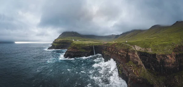 Letecký dron panorama vesnice Gasadalur a Mulafossur jeho ikonický vodopád, Vagar, Faerské ostrovy, Dánsko. V severním Atlantickém oceánu je to drsné. Bujná zeleň během léta. — Stock fotografie