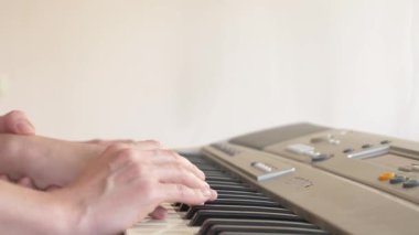 yakın çekim. bir piyano öğretmeni piyano çalmak için bir çocuk elleri ayarlama öğretir. 4k, ağır çekim