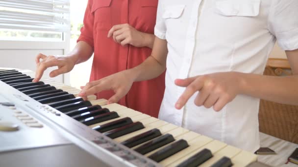 Primo piano. suonare il pianoforte in quattro mani. mani femminili e bambini giocano insieme su un sintetizzatore. 4k, rallentatore — Video Stock