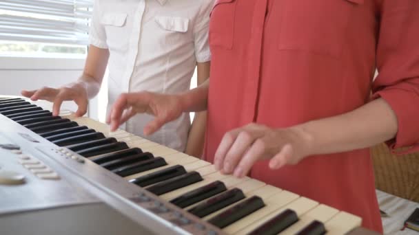 Крупним планом. грати на піаніно в чотирьох руках. жіночі та дитячі руки грають разом на синтезаторі. 4k, повільний рух — стокове відео