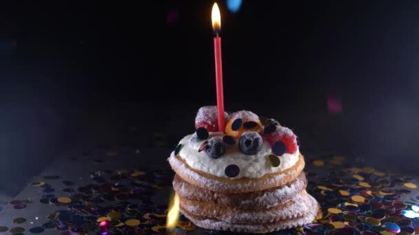 Férias, celebração e conceito de festa - cupcake de aniversário com uma queima de velas sobre fundo preto, confete. Confetti para uma festa. 4k, câmera lenta — Vídeo de Stock