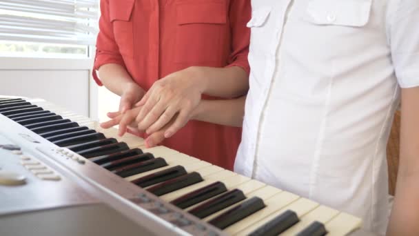 Close-up. um professor de piano ensina uma criança a tocar piano, colocando as mãos. 4k, câmera lenta — Vídeo de Stock