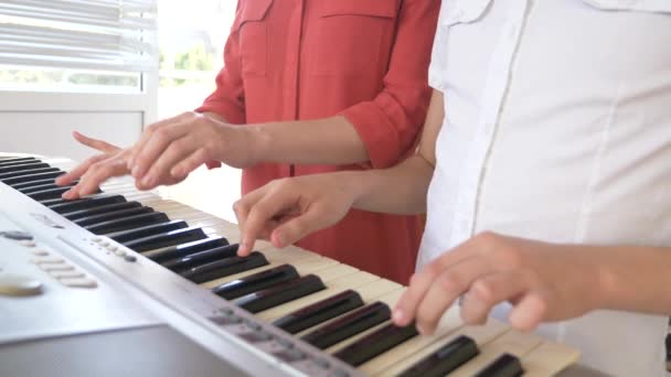 Primer plano. tocando el piano en cuatro manos. manos femeninas y niños juegan juntos en un sintetizador. 4k, cámara lenta — Vídeos de Stock