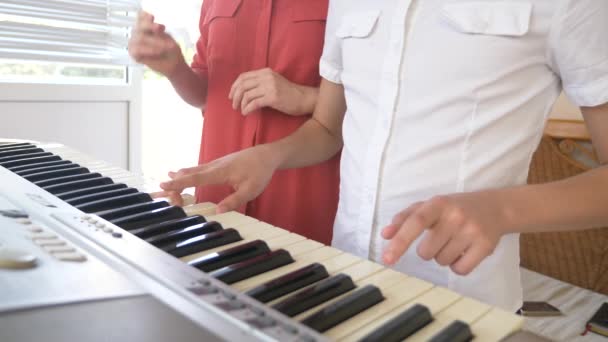 Primo piano. suonare il pianoforte in quattro mani. mani femminili e bambini giocano insieme su un sintetizzatore. 4k, rallentatore — Video Stock