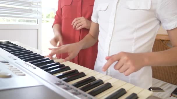 Detail. hra na klavír ve čtyřech rukou. ženské a dětské ruce hrát společně na syntezátor. 4k, pomalý pohyb — Stock video