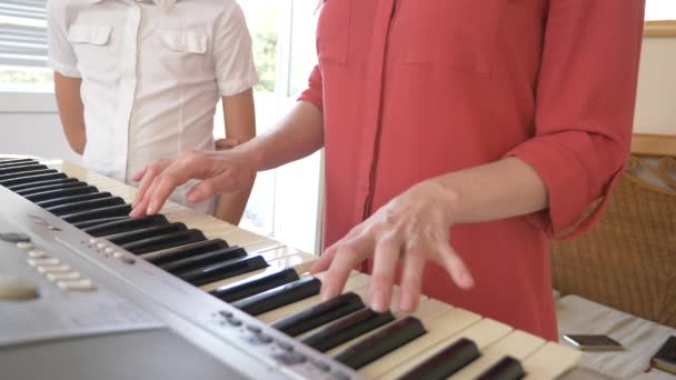 Close-up. piano spelen in vier handen. vrouwelijk en childs handen spelen samen op een synthesizer. 4k, slow-motion — Stockvideo
