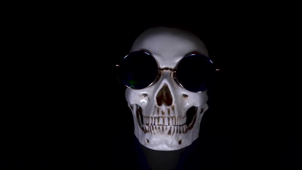 Schedel in ronde zonnebril op een zwarte achtergrond. Close-up. 4k, dolly schot, defocusing, vervagen. — Stockvideo