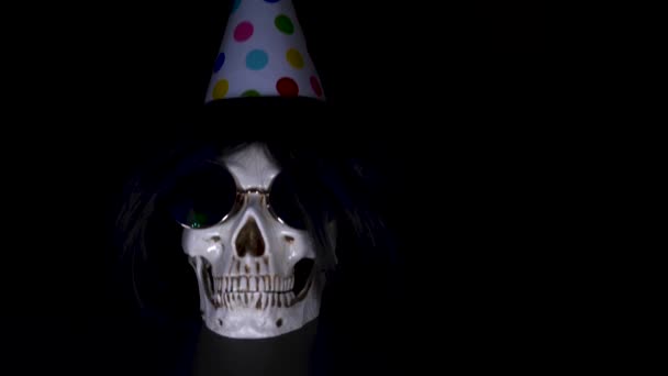 Halloween. el cráneo en una gorra festiva sobre un fondo negro. 4k, dolly shot . — Vídeo de stock