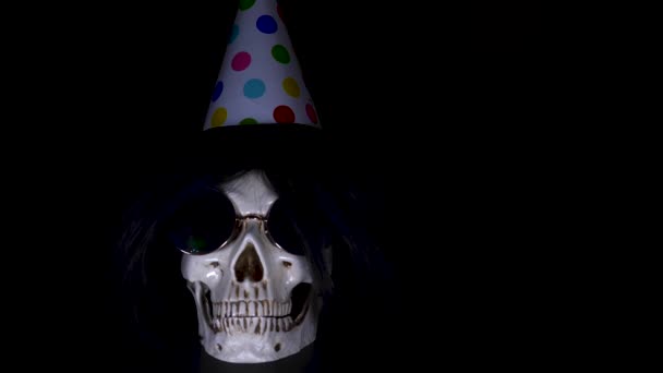 Halloween. el cráneo en una gorra festiva sobre un fondo negro. 4k, dolly shot . — Vídeo de stock