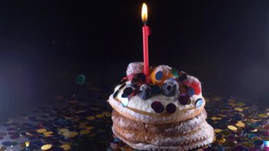 tatil, kutlama ve parti genel kavram - bir yanma ile Doğum günü kek siyah arka plan üzerinde konfeti mumlar. Konfeti bir parti için. süper ağır çekim