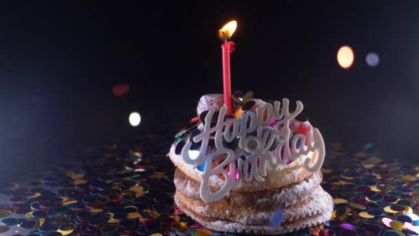 Vacances, célébration et concept de fête cupcake d'anniversaire avec une bougie allumée sur fond noir, confettis. Des confettis pour une fête. super ralenti — Video