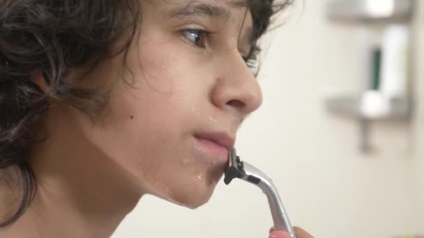 Подростковые бритья в первый раз, мальчик-подросток наносит пену для бритья, кожу, крем, лицо, 4k, крупным планом — стоковое видео