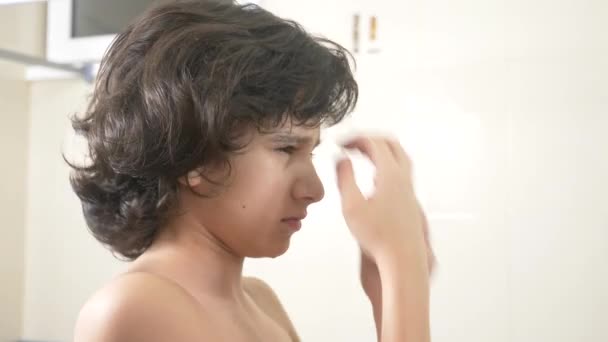 Carino ragazzo spazzolare i capelli ricci davanti allo specchio del bagno. 4k — Video Stock