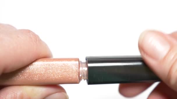 gros plan, les mains féminines ouvrent un tube avec du brillant à lèvres. 4k, au ralenti 