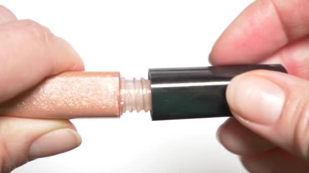 Close-up, as mãos femininas abrem um tubo com lustro de lábio. 4k, câmera lenta — Vídeo de Stock