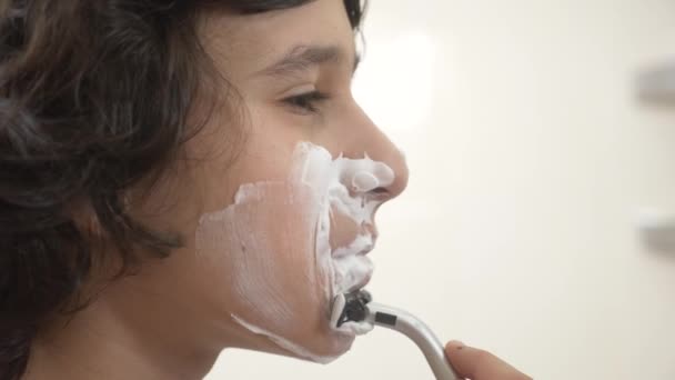 Підліток голиться перший раз, хлопчик-підліток застосовує піну для гоління, скінкард, крем, обличчя, 4k, крупним планом — стокове відео