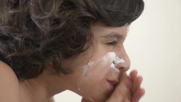 Подростковые бритья в первый раз, мальчик-подросток наносит пену для бритья, кожу, крем, лицо, 4k, крупным планом — стоковое видео
