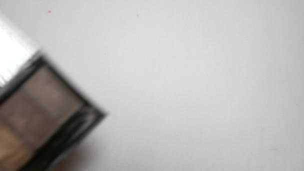 Kvinnlig hand ögonskugga tofs på vit bakgrund isolering. 4k, Slowmotion — Stockvideo