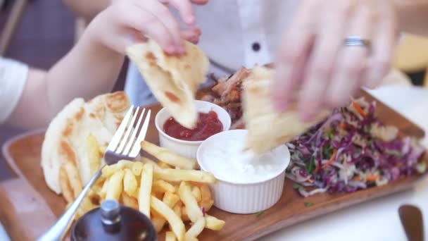 4k, Nahaufnahme. Vater und seine kleine Tochter essen Fast Food auf der Terrasse eines Schnellrestaurants. — Stockvideo