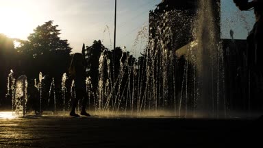 Çocuk siluetleri bir yaz günü kentin fıskiyede oynamak. 4k.