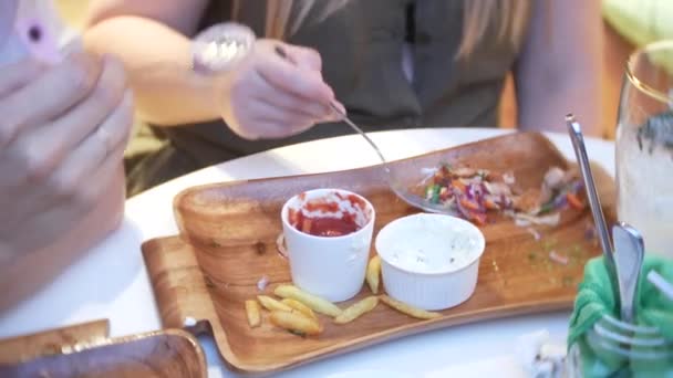 Primer plano, las manos femeninas con tenedores toman comida rápida de un plato de madera. 4k . — Vídeos de Stock