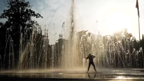 Las siluetas de los niños juegan en la fuente de la ciudad en un día de verano. 4k . — Vídeos de Stock