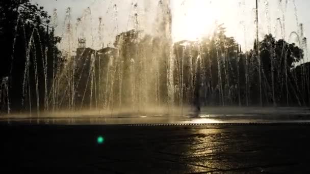 Sylwetki dzieci grać w fontannie siedzib w letni dzień. 4k. — Wideo stockowe