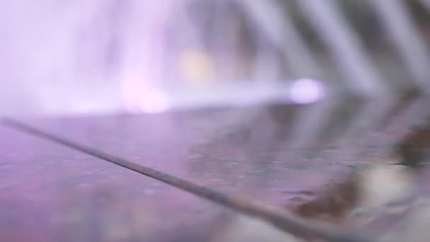 Una fontana con illuminazione ad acqua colorata, la sera. primo piano, sfocatura, 4k — Video Stock