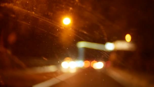 Auto venster nacht achtergrond defocus in beweging, door de vuile raam van de auto, verdorde vuil vlekken na de regen. 4k — Stockvideo