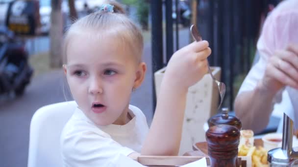 4k, närbild. Pappa och hans lilla dotter äter snabbmat på terrassen i en snabbmatsrestaurang. — Stockvideo