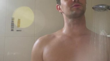 Banyoda duşta yakışıklı delikanlı. Penceresinden güneşin ışınları tarafından yaktı. 4k, ağır çekim.