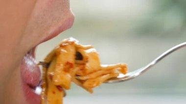 yakın çekim. profil erkek dudaklarında. adam kırmızı soslu spagetti yiyor. 4k, ağır çekim.