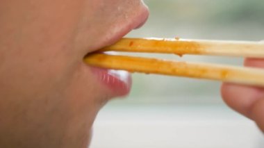 yakın çekim. profil erkek dudaklarında. yemek çubukları, 4 k, ağır çekim adam yiyor.