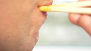 yakın çekim. profil erkek dudaklarında. adam kırmızı soslu spagetti yemek çubukları, yiyor. 4k, ağır çekim.