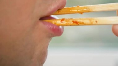 yakın çekim. profil erkek dudaklarında. yemek çubukları, 4 k, ağır çekim adam yiyor.