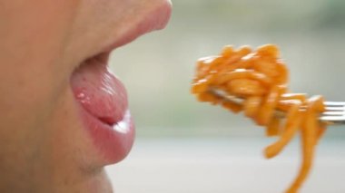 yakın çekim. profil erkek dudaklarında. adam kırmızı soslu spagetti yiyor. 4k, ağır çekim.