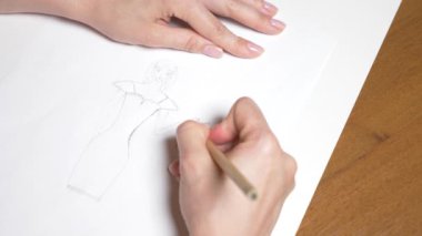 Ağır çekim. 4k, yakın çekim, en iyi görünüm. bir el bir kalemle çizer. bir kız elbise.