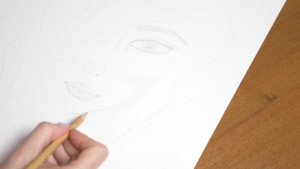 Une main féminine dessine le portrait d'une fille. 4k, gros plan. Au ralenti. vue d'en haut . — Video