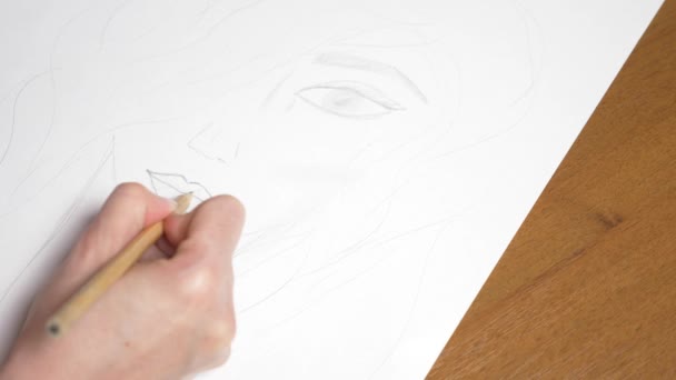 une main féminine dessine le portrait d'une fille. 4k, gros plan. Au ralenti. vue d'en haut .