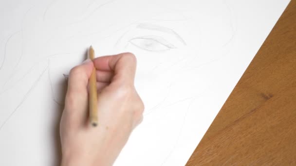 une main féminine dessine le portrait d'une fille. 4k, gros plan. Au ralenti. vue d'en haut .