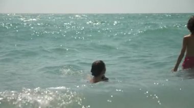 mutlu çocuk deniz dalgaları içine atlama vardır. 4k, ağır çekim.