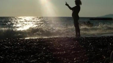 Gün batımında kumsalda oynayan mutlu insanların tanınamaz haldeki silueti..