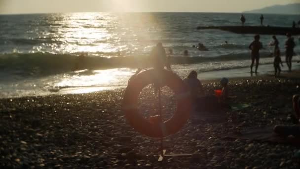 Genel bir plajda Lifebuoy üzerinde. insan siluetleri. Bronzlaşma, yüzme, turizm, dinlenme ve rahatlama sun — Stok video